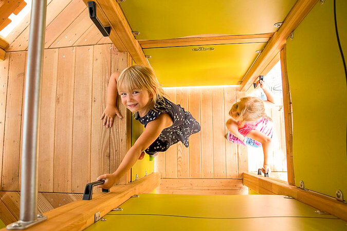 Spielplätze für Wohnanlagen – Zwei Mädchen klettern im Innern eines Kletterturms.